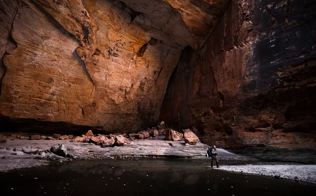 A woman sitting on a high alpine ridge, looking out over a vast mountain landscape